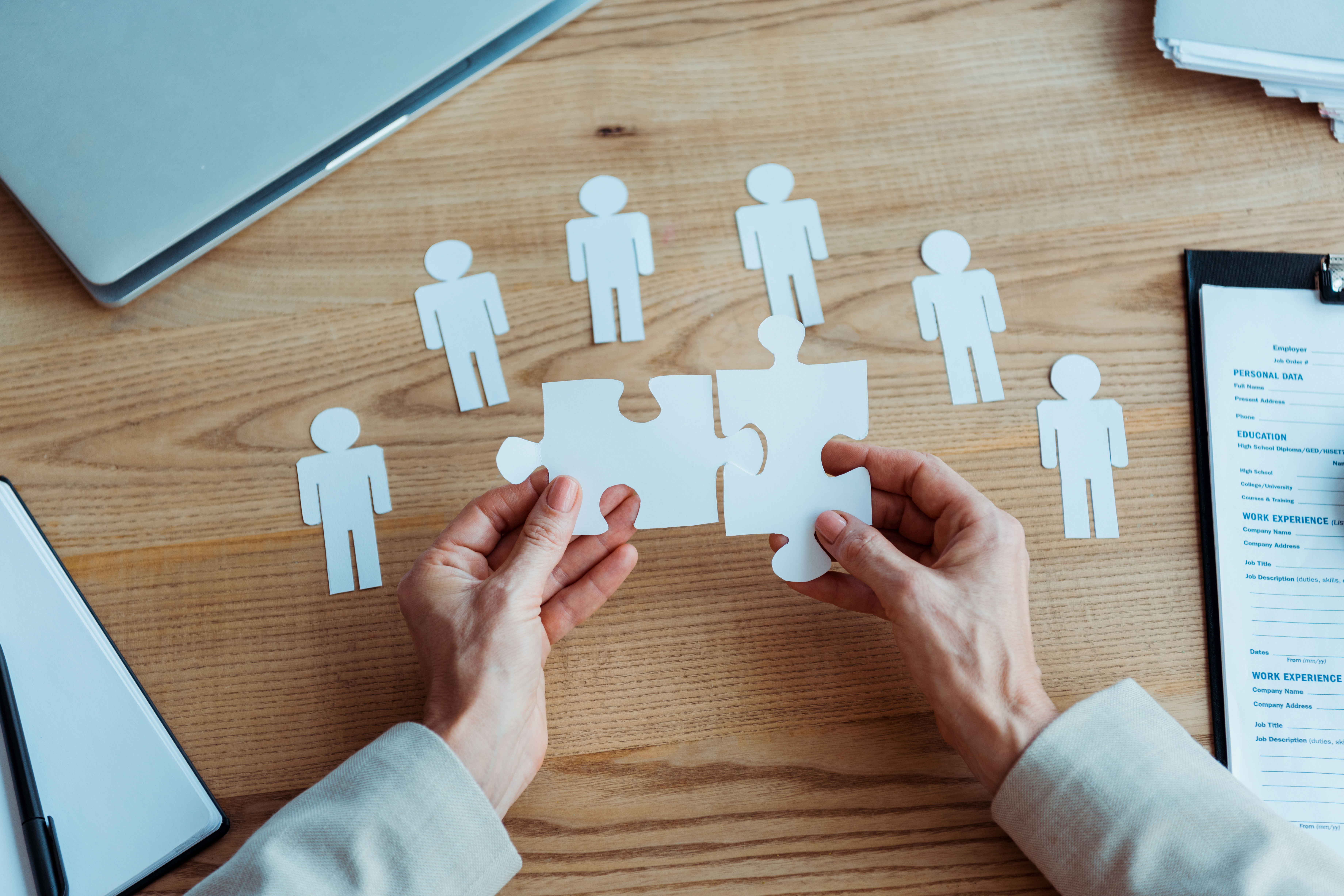 cropped view of woman holding jigsaw puzzle pieces near table