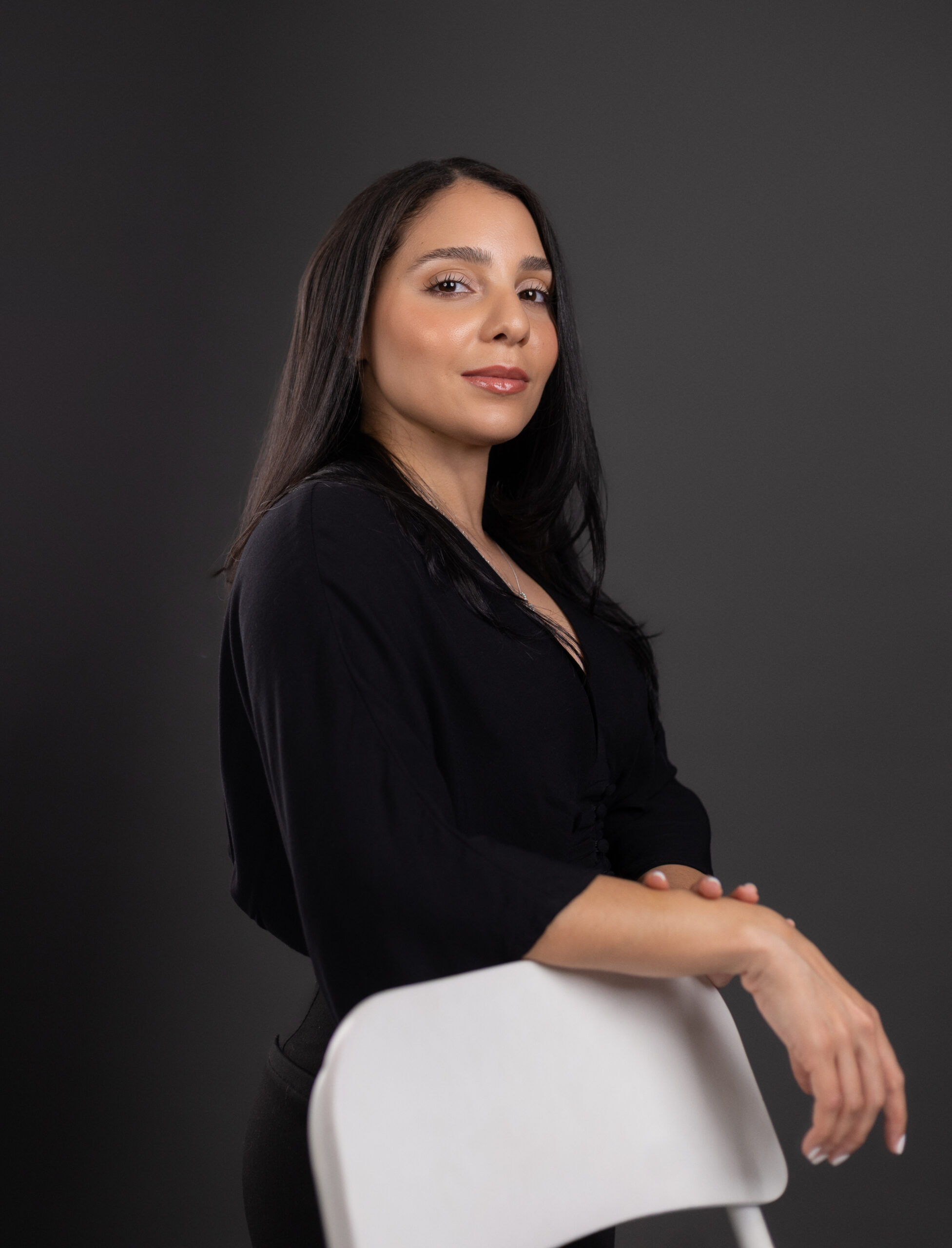 Taldman Payan Image of Taldman Payan, founder of Solutions360corp leaning against a chair, showing her side profile
